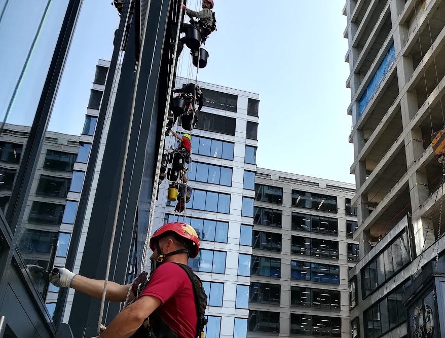 Rope access professionals working on a glass building facade