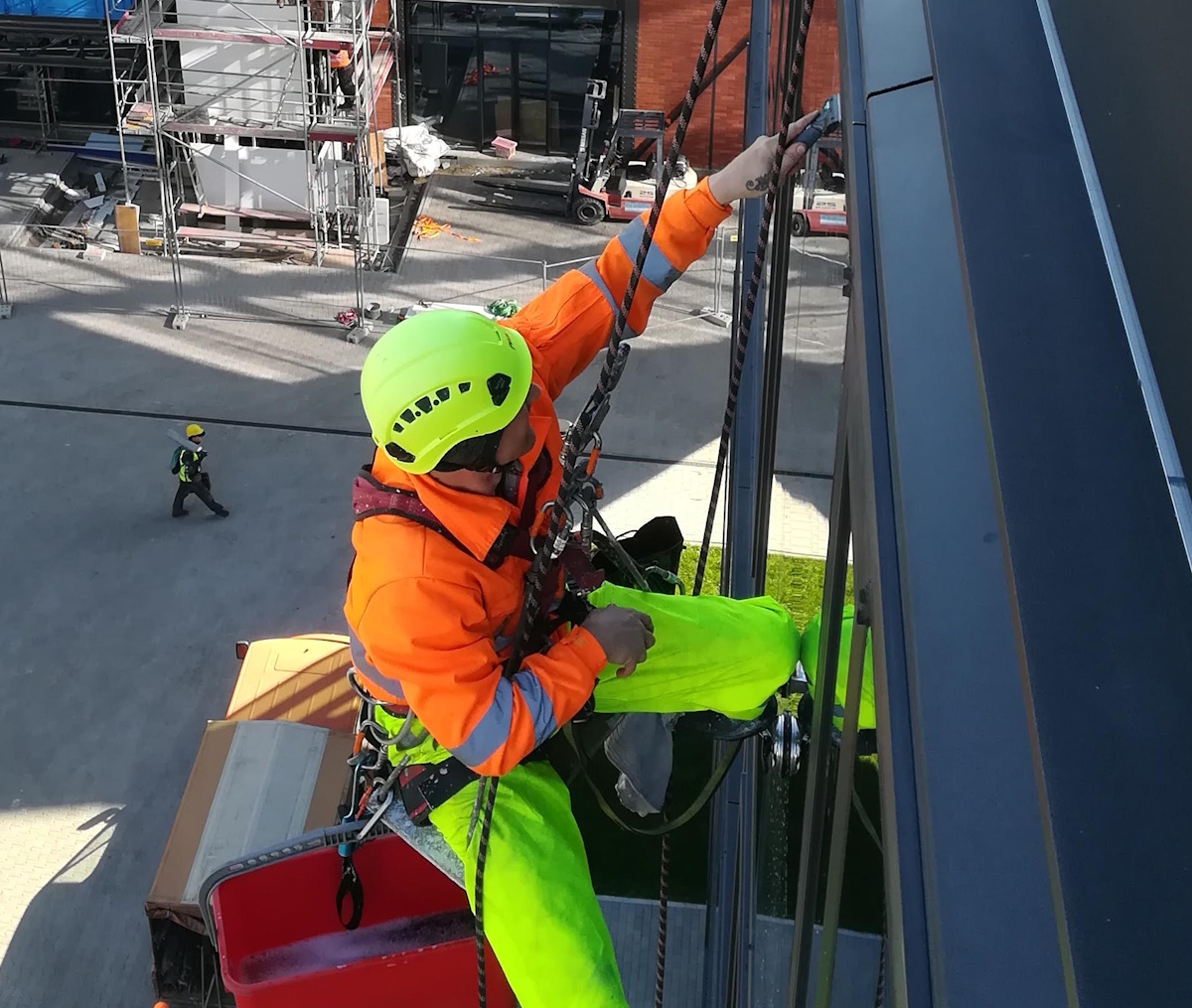 Rope access technician cleaning a high-rise window